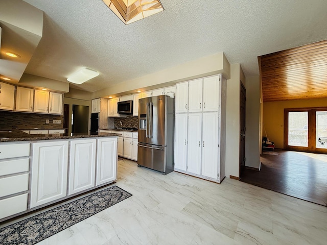 kitchen featuring high end refrigerator, dark stone countertops, marble finish floor, white cabinetry, and backsplash