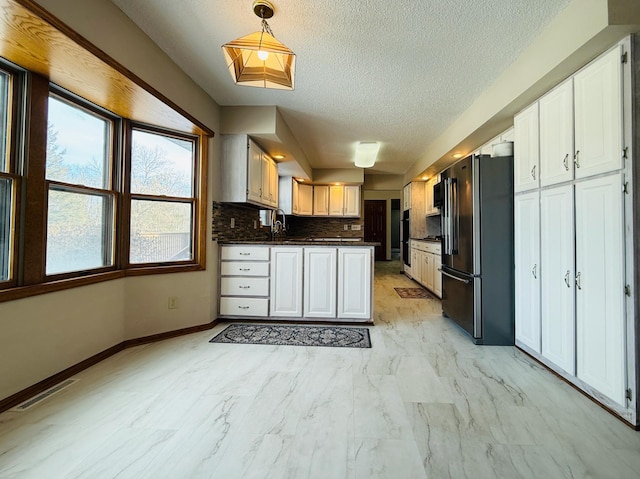 kitchen featuring visible vents, dark countertops, high quality fridge, white cabinetry, and pendant lighting