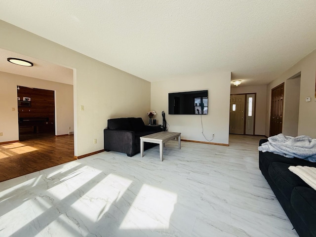 living area featuring a textured ceiling, marble finish floor, and baseboards