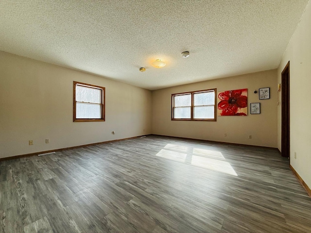 empty room with a textured ceiling, baseboards, and wood finished floors