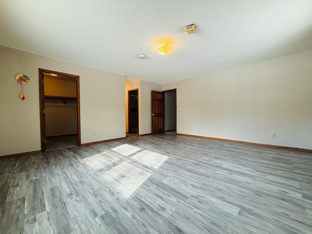 unfurnished room featuring light wood-style floors, a textured ceiling, and baseboards