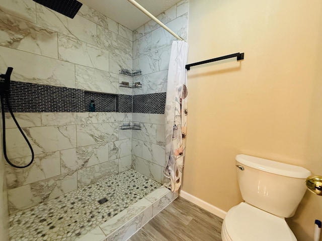 full bathroom featuring a stall shower, baseboards, toilet, and wood finished floors