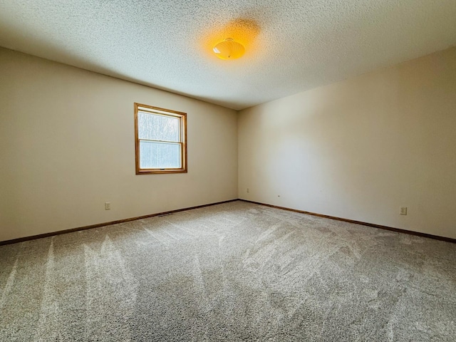 carpeted spare room featuring baseboards and a textured ceiling