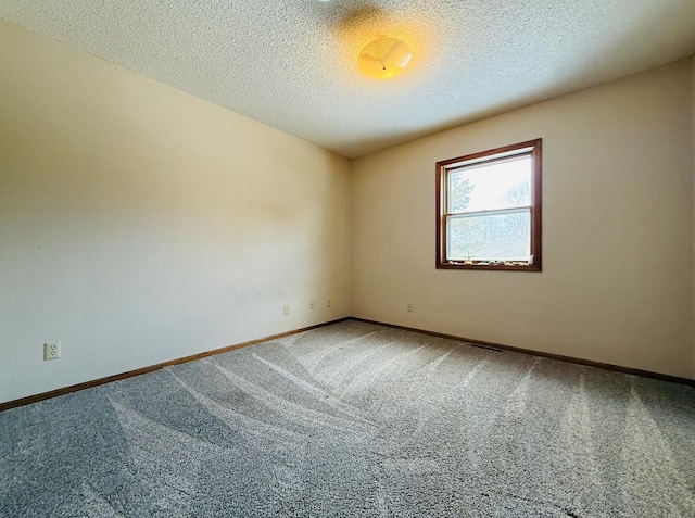 carpeted empty room featuring baseboards and a textured ceiling