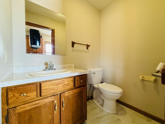 half bath with baseboards, vanity, and toilet