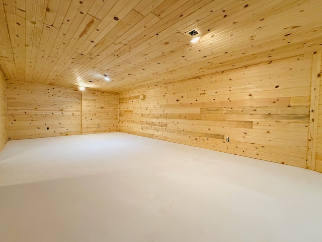 bonus room featuring finished concrete floors, wooden ceiling, and wooden walls