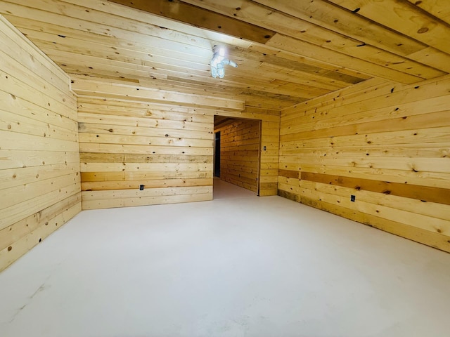 additional living space with concrete floors, wooden ceiling, and wood walls