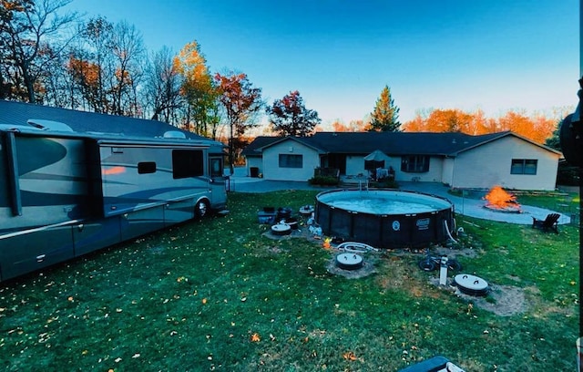 view of front of property featuring a fire pit, a front yard, and an outdoor pool