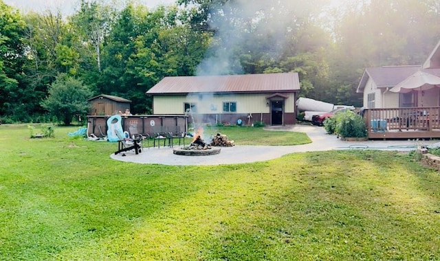 back of house with an outdoor fire pit, a lawn, and a wooden deck