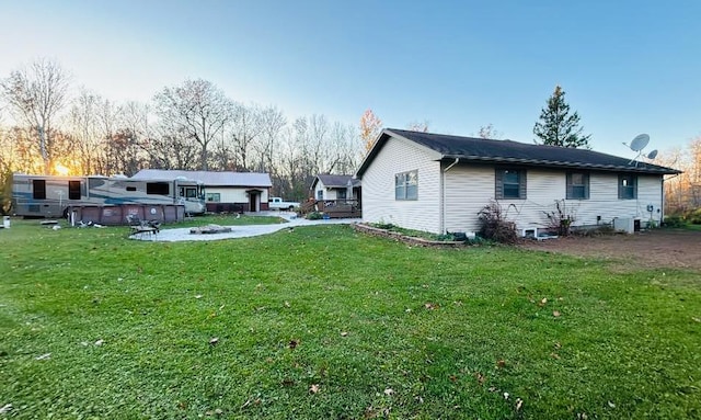 rear view of house featuring central AC, a lawn, and an outdoor pool