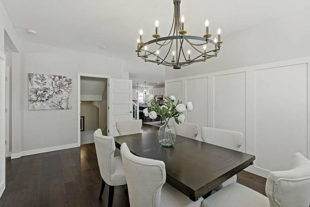 dining room with a notable chandelier, a decorative wall, and dark wood-style flooring