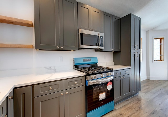 kitchen with stainless steel appliances, gray cabinets, light wood finished floors, and open shelves