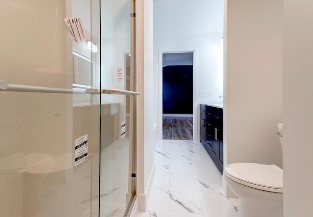 bathroom with toilet, vanity, baseboards, marble finish floor, and a shower stall