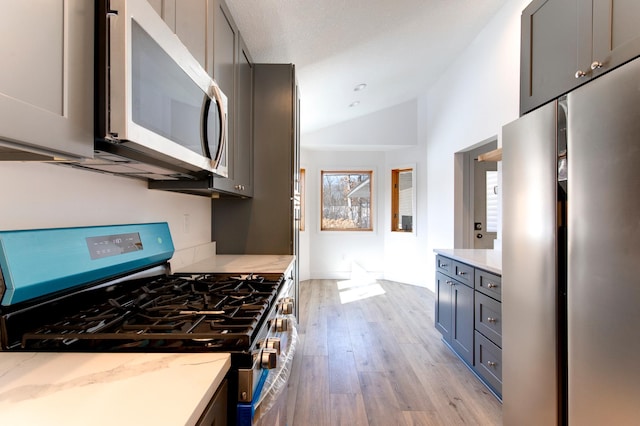 15153 Cates Lake Dr, Prior Lake, MN 55372 - kitchen featuring stainless steel appliances, light wood-style floors, vaulted ceiling, light stone counters, and gray cabinetry