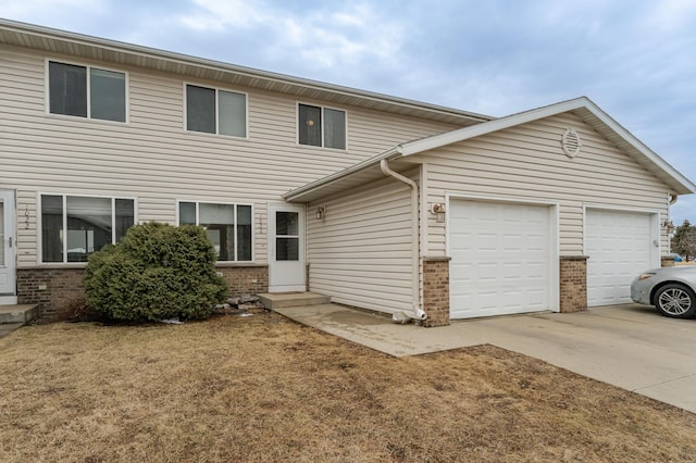 view of front of house featuring an attached garage, entry steps, concrete driveway, and brick siding