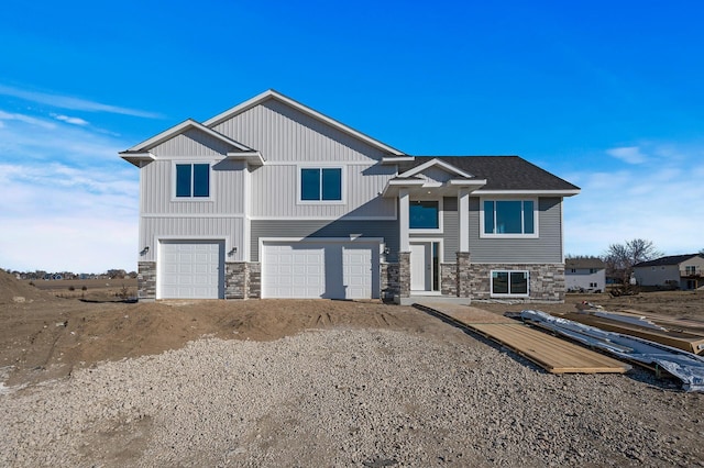 view of front of property with a garage, stone siding, roof with shingles, and gravel driveway