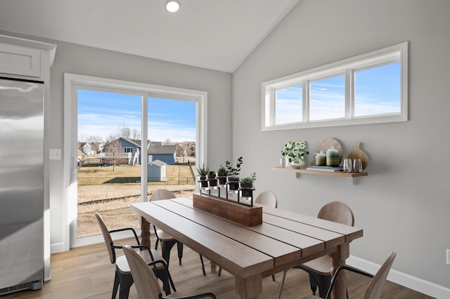 dining space with vaulted ceiling, light wood-type flooring, plenty of natural light, and baseboards