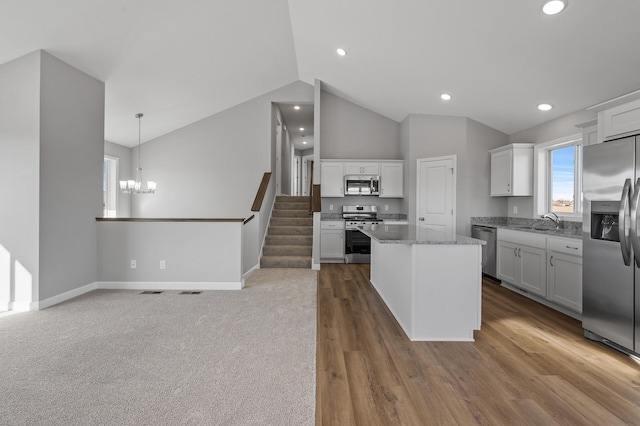 kitchen with hanging light fixtures, appliances with stainless steel finishes, white cabinetry, and a center island