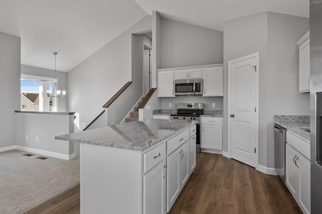 kitchen featuring a center island, stainless steel appliances, hanging light fixtures, white cabinetry, and a chandelier