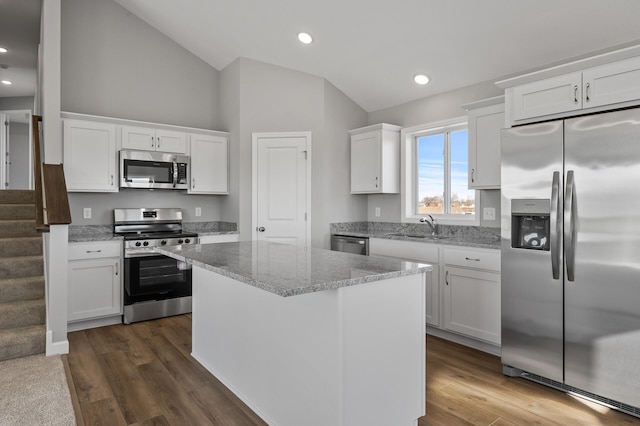 kitchen featuring vaulted ceiling, stainless steel appliances, a kitchen island, and white cabinets