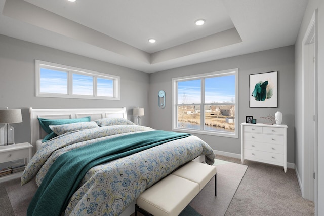 carpeted bedroom featuring recessed lighting, a raised ceiling, multiple windows, and baseboards