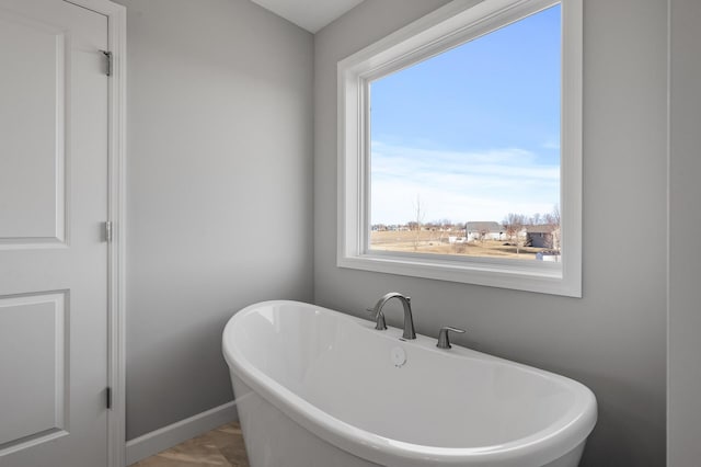 bathroom with a soaking tub and baseboards