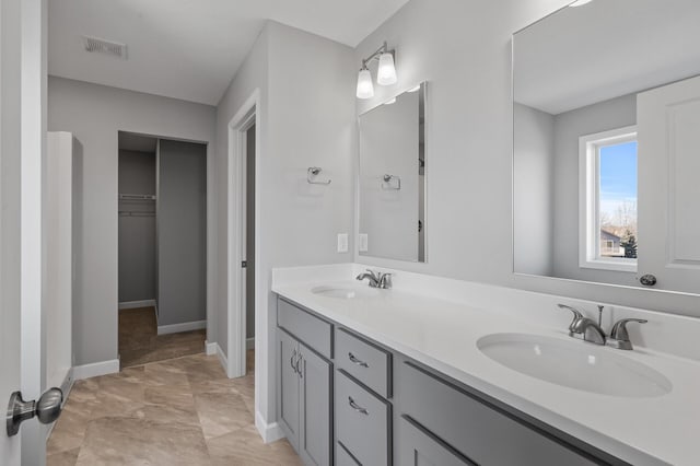 full bathroom with visible vents, double vanity, a sink, and a walk in closet