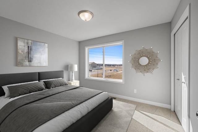 bedroom featuring light carpet, a closet, and baseboards