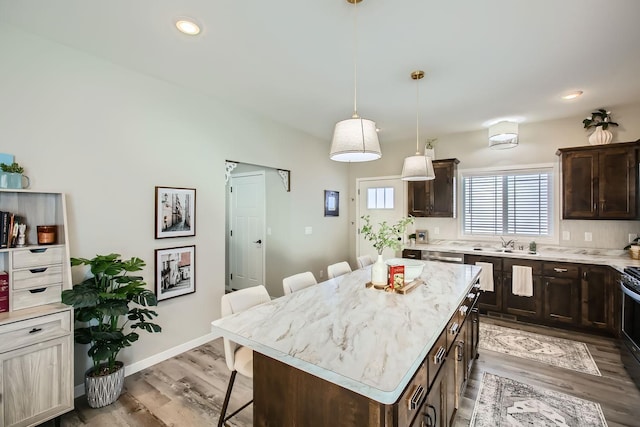 kitchen with a kitchen bar, light countertops, dark brown cabinets, and a center island