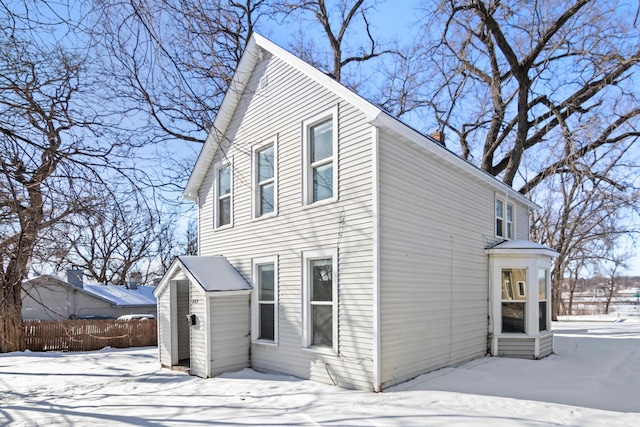 view of snowy exterior with entry steps, fence, and a chimney