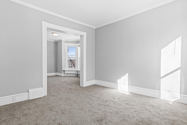 carpeted spare room with ornamental molding, visible vents, and baseboards