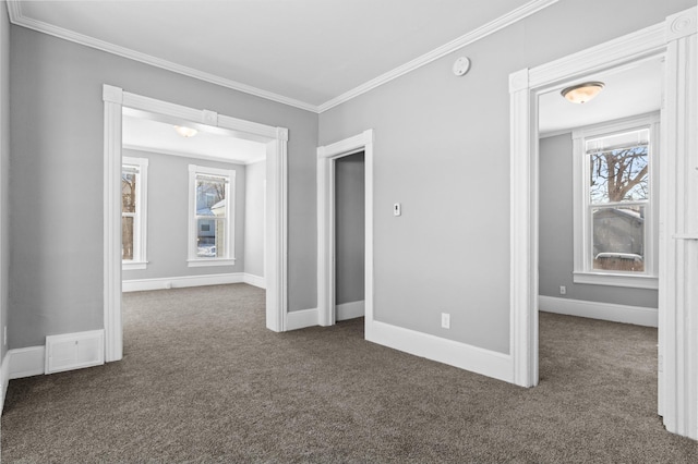 unfurnished room with baseboards, dark colored carpet, visible vents, and crown molding