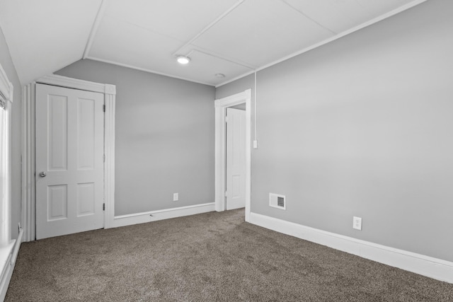 unfurnished bedroom with lofted ceiling, baseboards, visible vents, and carpet flooring