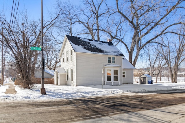 view of front of home with entry steps, a storage unit, a chimney, and an outbuilding