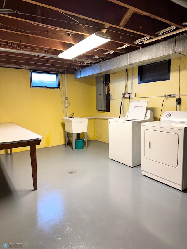 below grade area featuring a sink, washing machine and clothes dryer, and electric panel