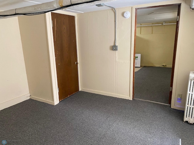 unfurnished bedroom featuring dark colored carpet and radiator heating unit