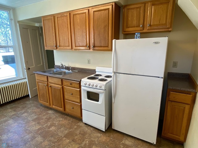 kitchen with white appliances, dark countertops, radiator, brown cabinets, and a sink