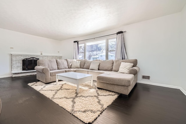 living area featuring dark wood-style floors, visible vents, a fireplace, and baseboards