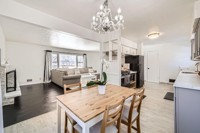 dining space with light wood-style flooring, visible vents, baseboards, and a notable chandelier