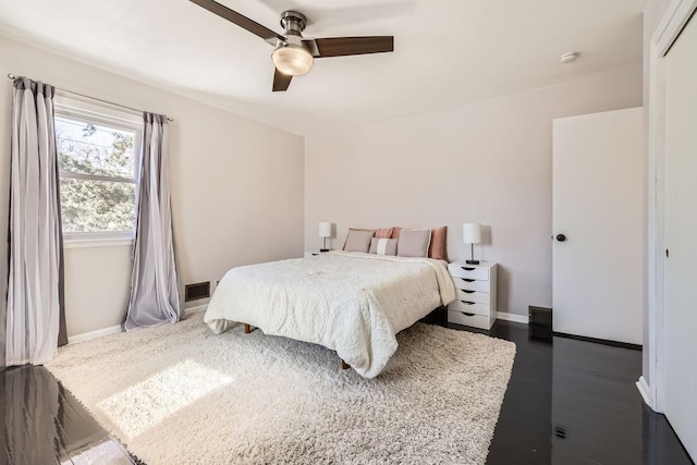 bedroom featuring ceiling fan, dark wood-style floors, visible vents, and baseboards