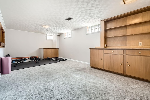 exercise area with light carpet, baseboards, and a textured ceiling