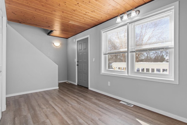 foyer entrance with light wood finished floors, wood ceiling, visible vents, and baseboards