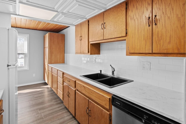 kitchen with tasteful backsplash, light countertops, freestanding refrigerator, a sink, and dishwasher