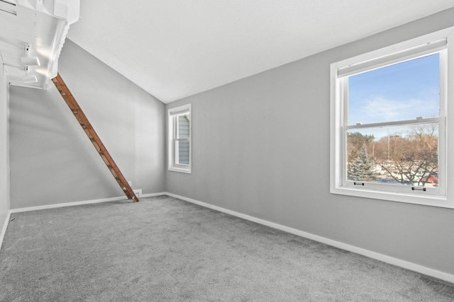 carpeted spare room featuring vaulted ceiling and baseboards