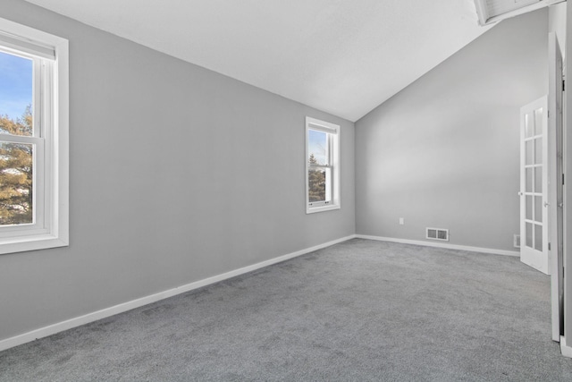 carpeted empty room with lofted ceiling, baseboards, and visible vents