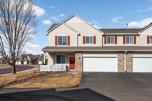 view of front of home with an attached garage, brick siding, covered porch, and driveway