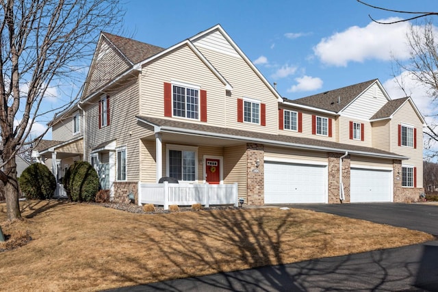 view of front of house with aphalt driveway, covered porch, brick siding, and roof with shingles