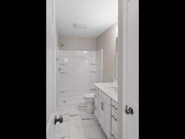 bathroom featuring marble finish floor, vanity, toilet, and walk in shower