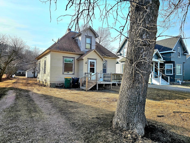 rear view of property with a shingled roof, a deck, and a chimney