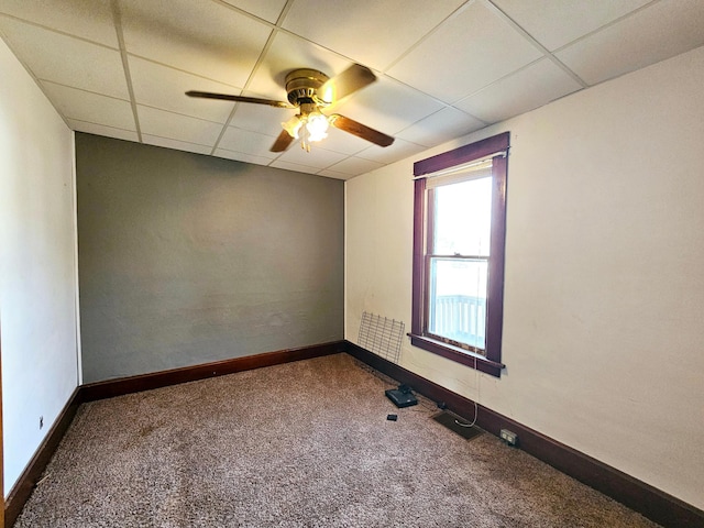 carpeted spare room featuring baseboards, a paneled ceiling, and ceiling fan